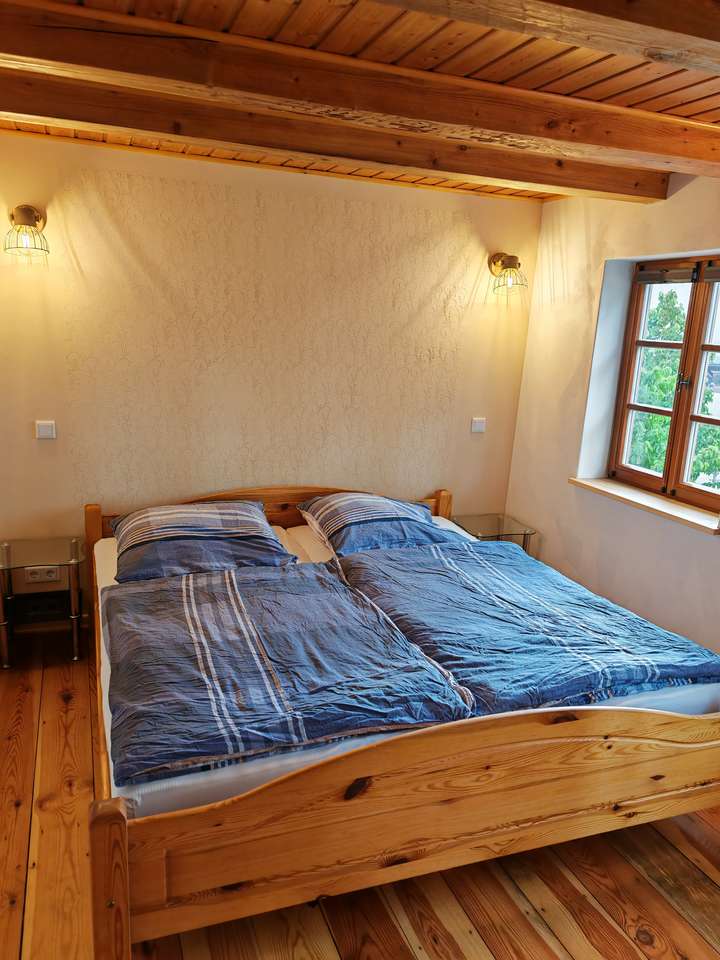 Bedroom with timber beams, wooden floorboards and a large double bed